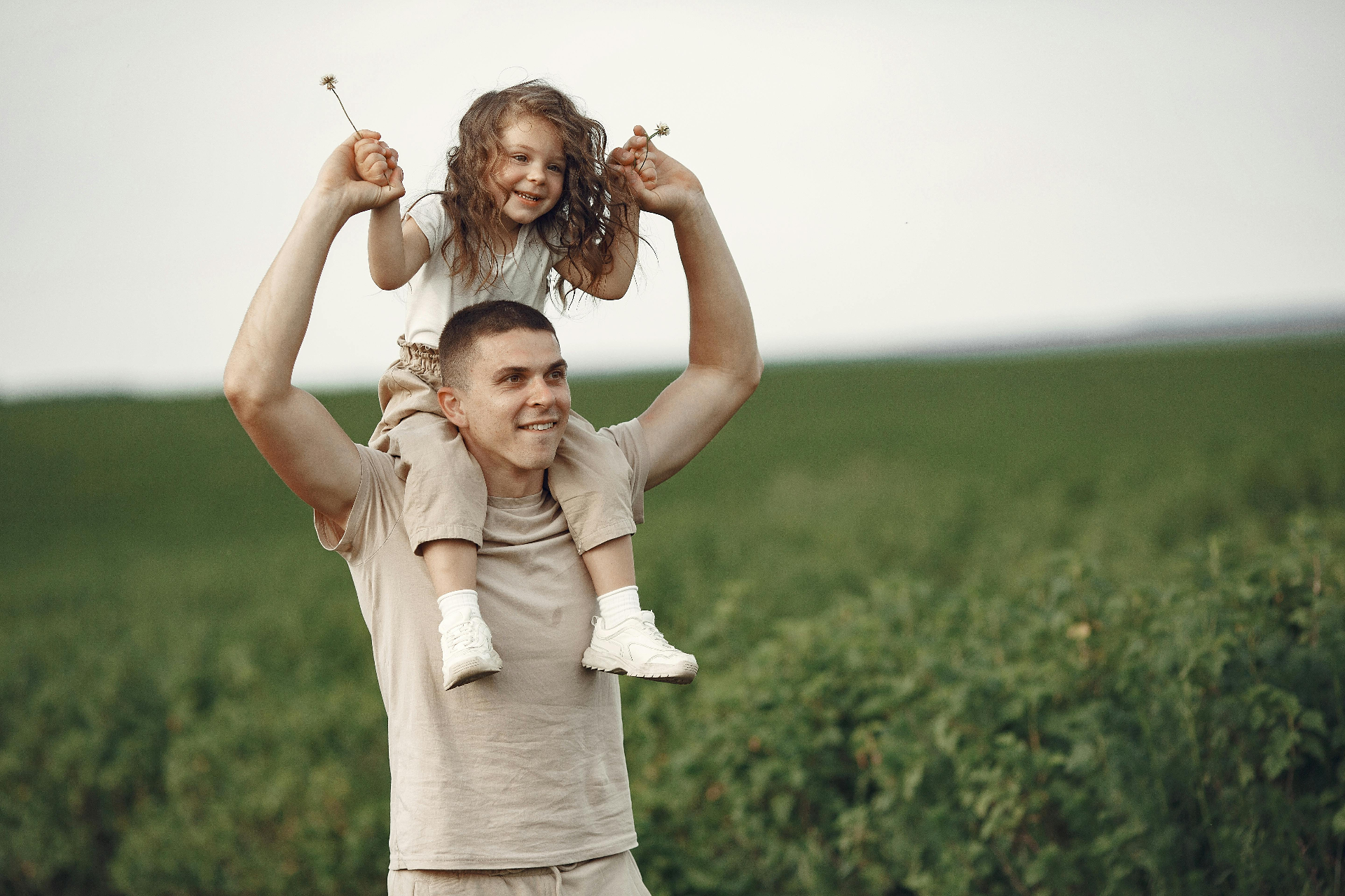 Father carrying daughter on shoulders in a field